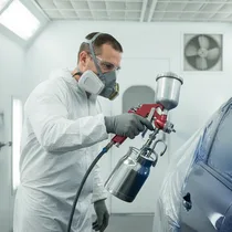 Ouvrier en combinaison utilisant le pistolet FINDER sur carrosserie.