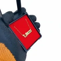 : Collier prénom personnalisé en or avec pendentif papillon dans son écrin rouge.