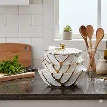 Ensemble de trois bols en porcelaine blanche et dorée empilés sur un plan de travail.