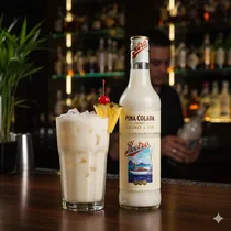 Verre de Pina Colada avec glaçons à côté de la bouteille Retro.