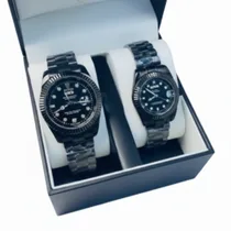 Coffret Montres Couple Noir Luxe noires pour homme et femme sur coussinets blancs.