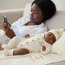 Bébé dormant avec bonnet à pompon et couverture Chanel.