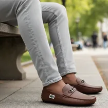 Paire de mocassins Lacoste marron portés avec un jean gris.