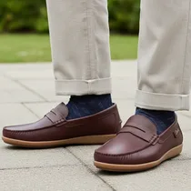 Paire de mocassins Clarks portée avec un pantalon habillé.