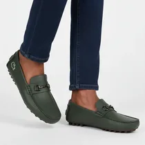 Mocassins Lacoste portés par un homme avec un jean bleu, vue rapprochée.