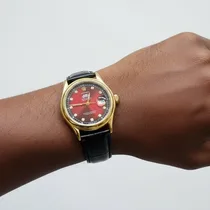 Zoom montre cadran rouge portée sur un poignet afro.