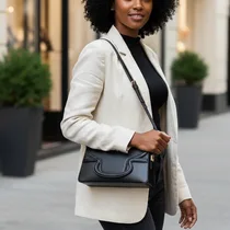 Sac à main noir Valentino porté en bandoulière par une femme afro.
