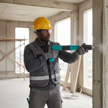 Ouvrier utilisant le pistolet cloueur manuel sur un mur béton.