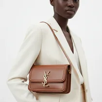 Femme portant le sac en bandoulière noir avec une tenue chic.