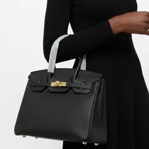 Sac à main noir de luxe porté au bras par une femme élégante.