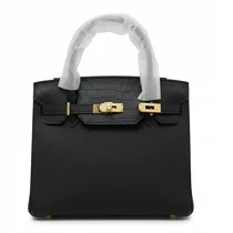 Gros plan sac à main noir cuir grainé avec fermoir doré métallique.
