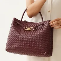 Femme portant le sac Bottega bordeaux à l'épaule.