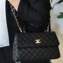 Femme portant le sac Chanel noir avec bandoulière chaîne et veste élégante.