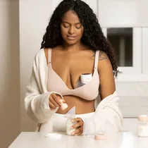 Maman afro souriante utilisant le tire-lait MY-379 sous son chemisier blanc