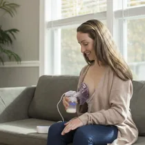 Femme utilisant le tire-lait Dr Gym confortablement sur un canapé.