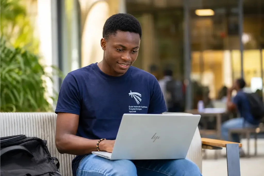 Étudiant camerounais avec un ordinateur portable sur les genoux