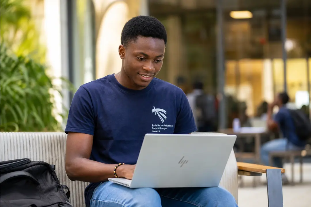Étudiant camerounais avec un ordinateur portable sur les genoux
